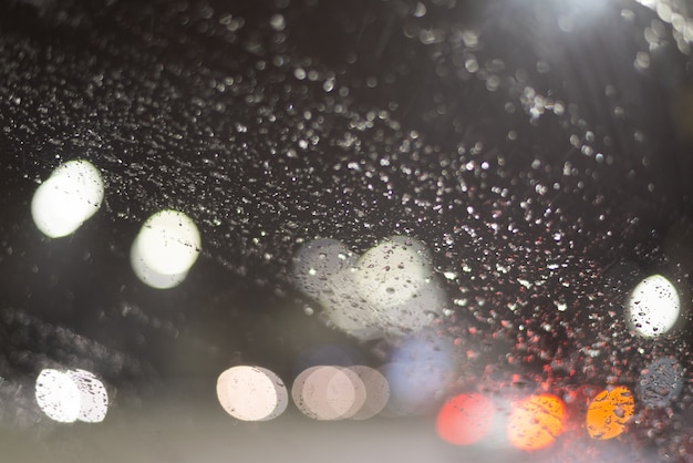 雨滴とライトで背景がぼやけています。