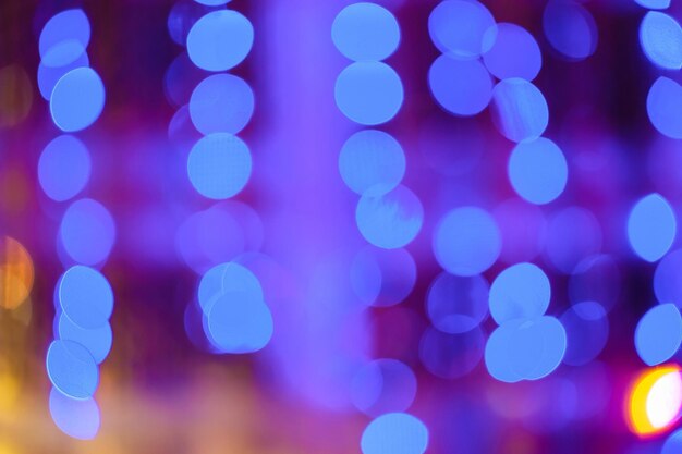 Blurred bokeh colorful lights lanterns holiday new year lighting on black background Christmas winter glitter shiny light bokeh in rainbow colors Holiday purple blue pink violet natural texture