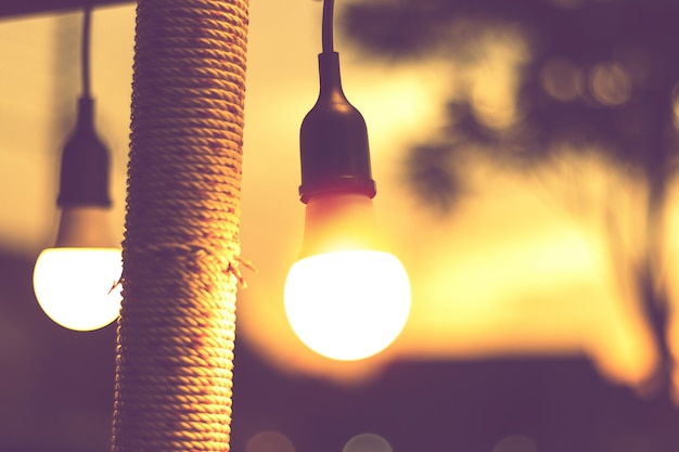 Foto luce vaga del bokeh sul tramonto con la decorazione gialla delle luci della corda nel ristorante della spiaggia