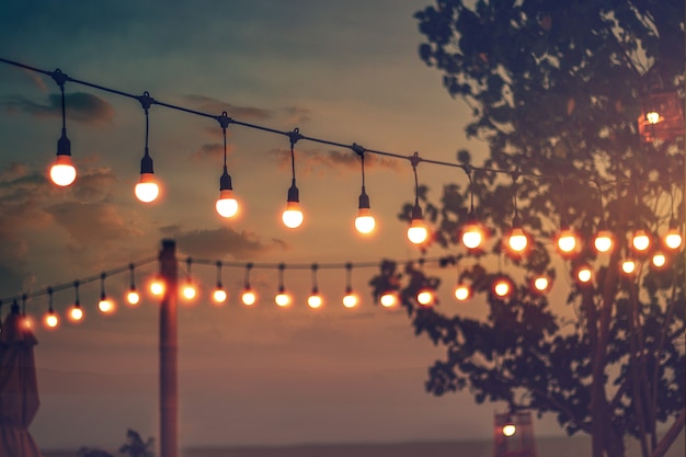 Luce vaga del bokeh sul tramonto con la decorazione gialla delle luci della corda nel ristorante della spiaggia