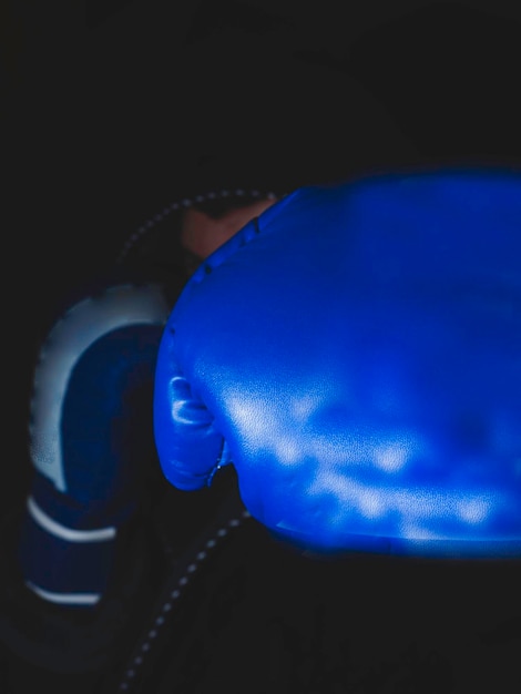 Blurred boxer in the dark gym and boxing kick focus on glove