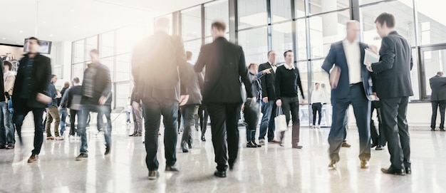 blurred business people standing and walking in a tradeshow hall. ideal for websites and magazines layouts