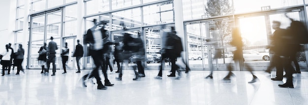 blurred business people walking in at a trade show floor, banner size. ideal for websites and magazines layouts