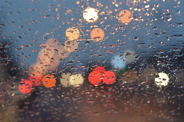 背景のために雨の中で曇った車の光