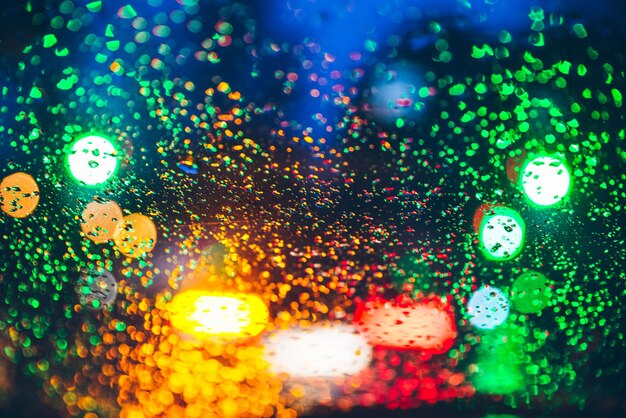 Photo blurred car light trough wet glass wet drops on glass