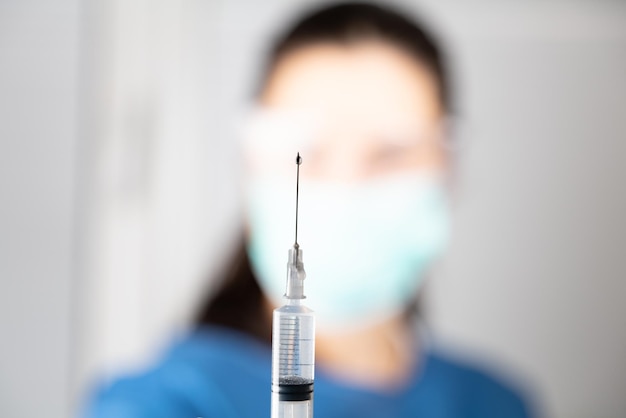 Blurred doctor and focus on syringe with needle