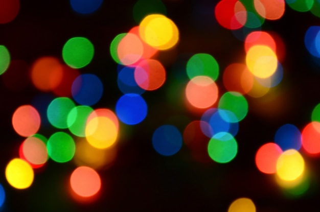 Photo blurred festive colorful lights over black useful as background.