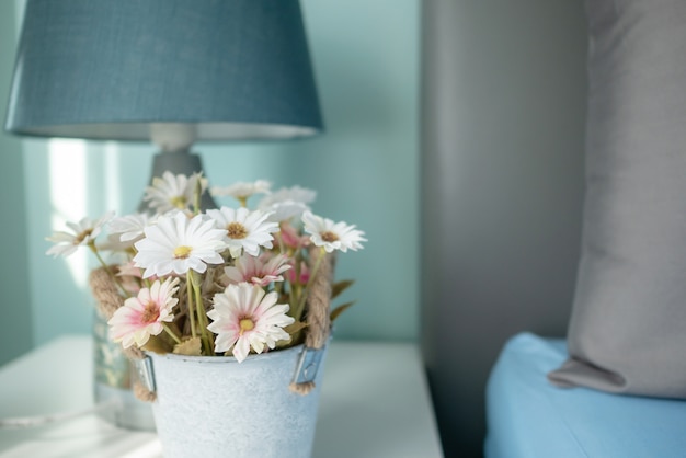 Foto fiori sfocati e la lampada sul tavolo con raggi di sole in camera da letto