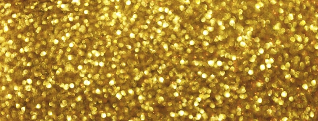 Photo blurred golden sparkling background from small sequins macro shiny yellow glittery bokeh of christmas garland