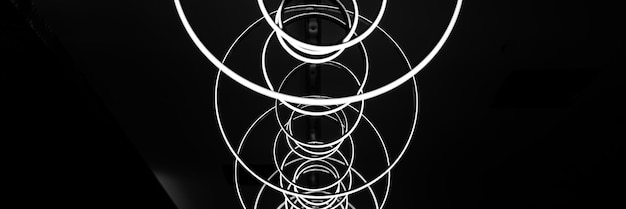 Blurred hanging lamp bulb in the form of rings blur abstract lighting modern pendant electricity round lamps chandelier glowing gray dim light inside a room tinted in black and white banner