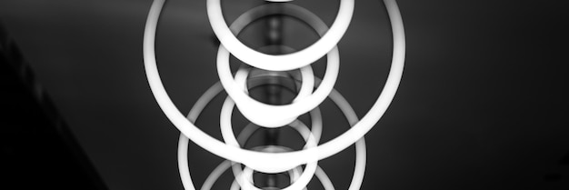 Blurred hanging lamp bulb in the form of rings blur abstract lighting modern pendant electricity round lamps chandelier glowing gray dim light inside a room tinted in black and white banner