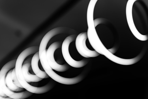 Blurred hanging lamp bulb in the form of rings blur abstract lighting modern pendant electricity round lamps chandelier glowing gray dim light inside a room tinted in black and white