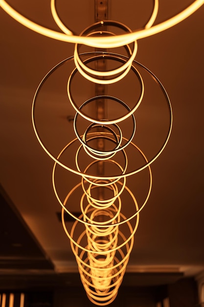 Blurred hanging lamp bulb in the form of rings blur beautiful abstract lighting under the ceiling from modern pendant electricity round lamps chandelier glowing golden yellow dim light inside a room