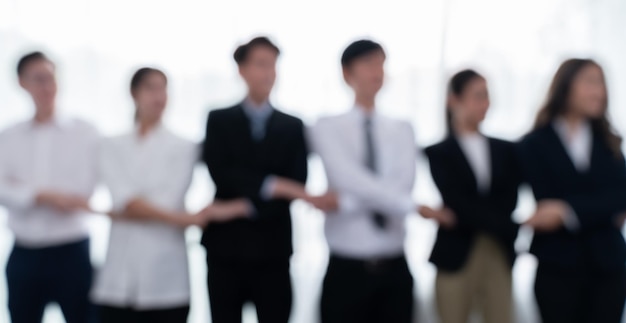 Blurred image of businesspeople holding hand in line as office of harmony