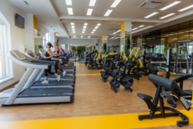 Blurred image of a modern gym with people exercising. Sports background. Gym interior