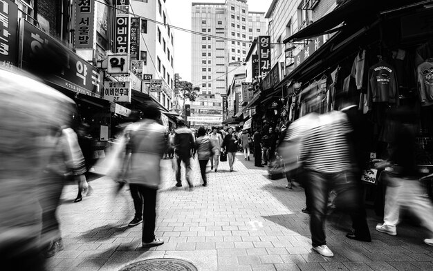 Photo blurred image of people walking on street amidst buildings