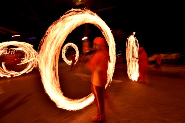 Photo blurred image of woman standing by illuminated lighting equipment at night