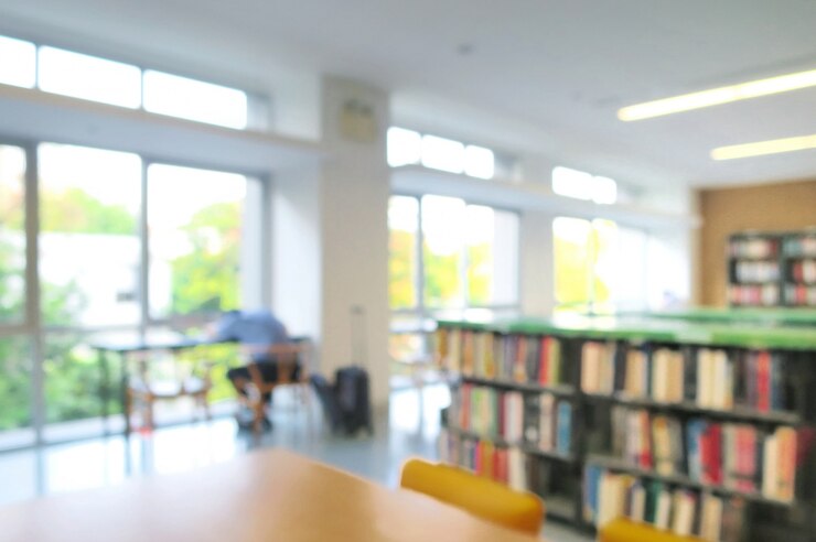 Photo 本棚の中の本と図書館のインテリアのぼやけ。男子学生が昼寝をする。