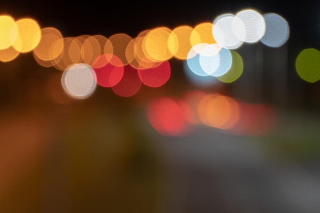 Blurred lights of the night city with a view of the roadway multicolored lights of city lanterns in out of focus bright abstract background on the desktop