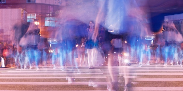 Foto movimento sfocato della folla che attraversa la strada della città di notte