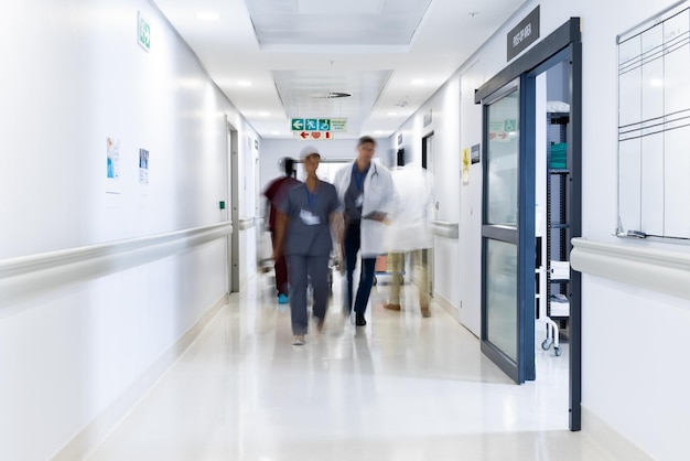 Blurred motion of diverse doctors and medical staff in busy hospital corridor, copy space. Hospital, medical and healthcare services.
