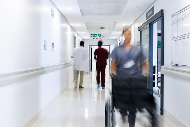 Blurred motion of diverse doctors and medical staff in busy hospital corridor, copy space. Hospital, medical and healthcare services.