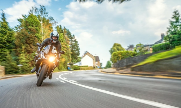 Foto movimento sfocato di un uomo in moto sulla strada contro un cielo nuvoloso