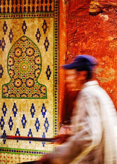 Photo blurred motion of man walking against patterned wall