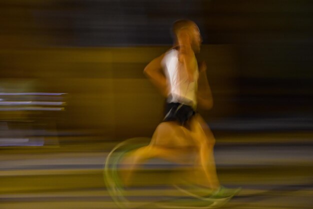 写真 夜に道路を走っている男性アスリートの昧な動き