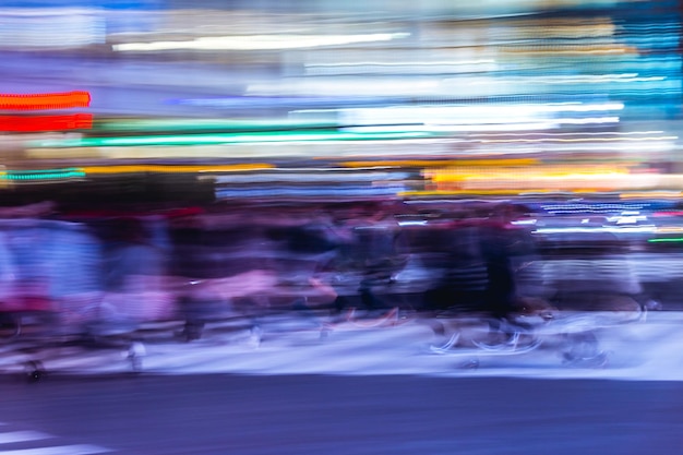 写真 夜の通りで人々の動きがぼやけている