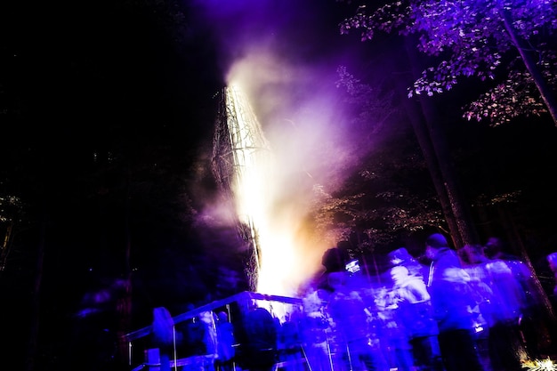 Photo blurred motion of people by campfire in forest at night