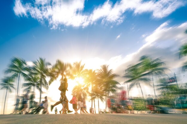 Blurred motion of people walking at beach against sky during sunset