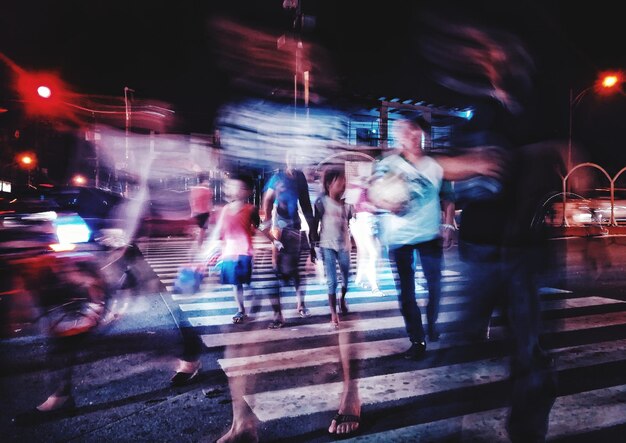 Photo blurred motion of people walking on illuminated street at night