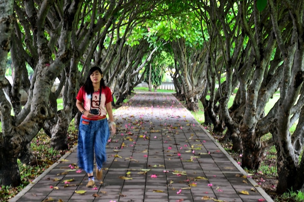 Photo blurred of motion of thai woman walking in frangipani trees tunnel at nan thailand