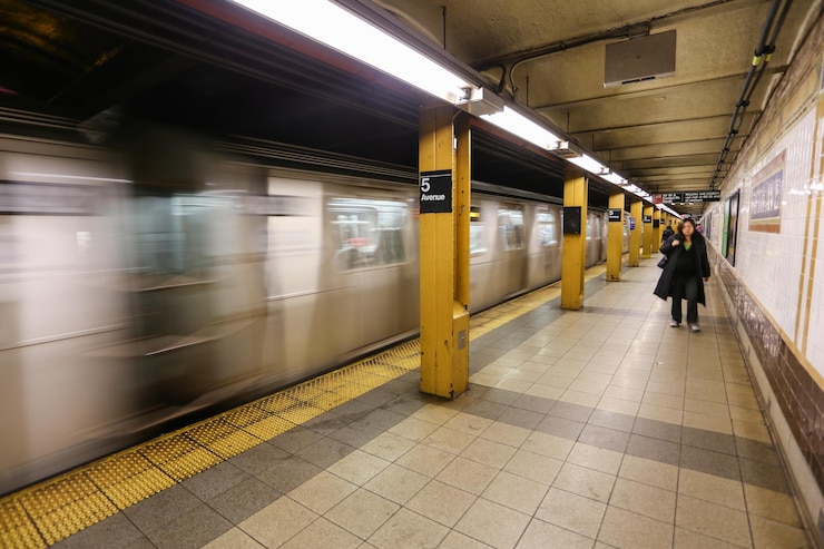 Photo blurred motion of train by woman walking at railroad station