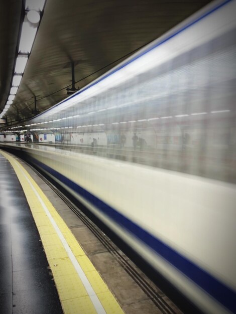 Foto movimento sfocato del treno sulla piattaforma della stazione ferroviaria