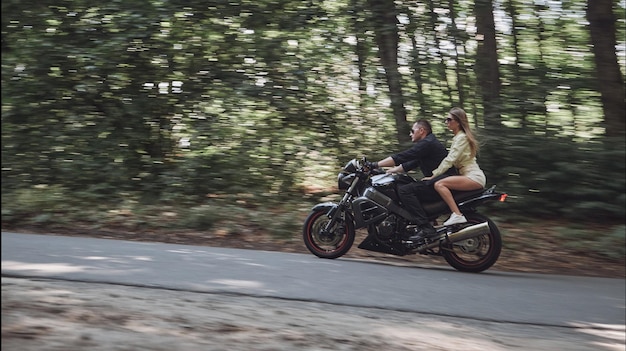 バイクに乗ったぼやけた動きの若いカップルヘルメットなし高速で危険なdriviで道路に乗る