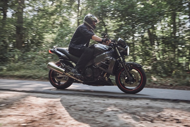 Blurred motion a young man biker in a helmet quickly rides at high speed on a forest road in motion