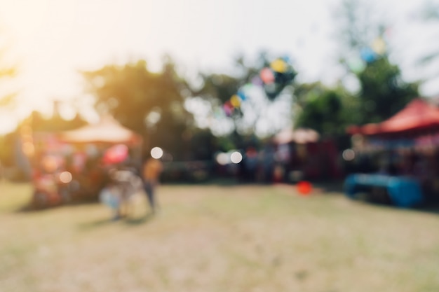 blurred people and sunlight at festival in the city park garden