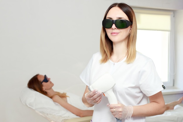 Blurred portrait of laser hair removal beautician and client at the reception body hair removal with diode laser