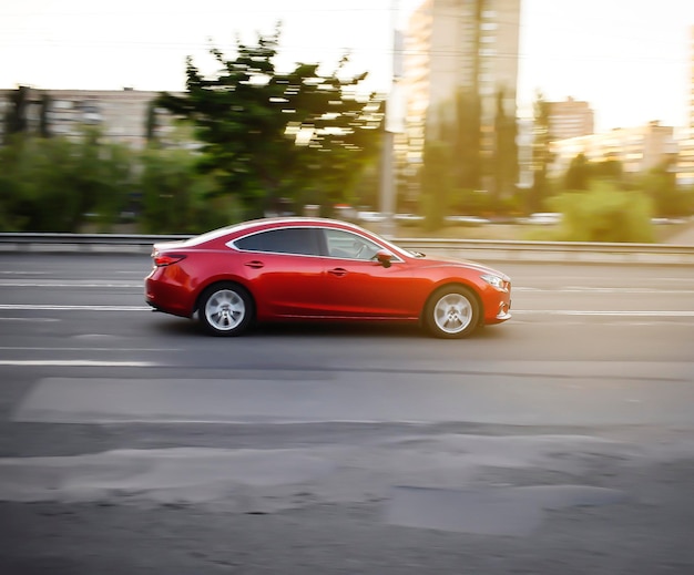 Blurred red sport car fast driving automobile moving on road highway blur effect selective focus