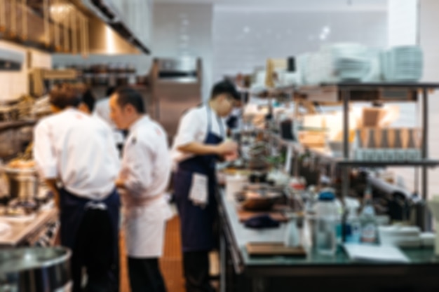 Blurred Restaurant chefs: Executive Chef cooking in the close kitchen with Sous Chefs (assistant).