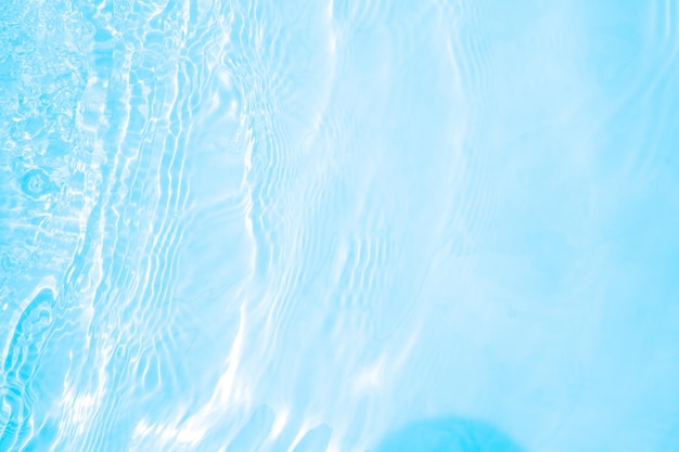 Blurred transparent blue colored clear calm water surface texture with splashes and bubbles Trendy abstract nature background Water waves in sunlight water background