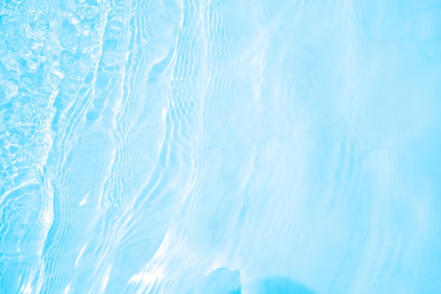 Blurred transparent blue colored clear calm water surface texture with splashes and bubbles Trendy abstract nature background Water waves in sunlight water background