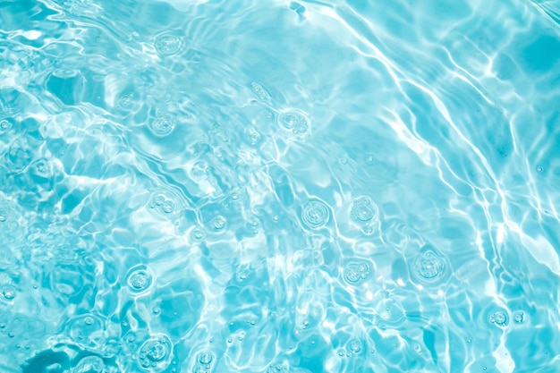 Blurred transparent blue colored clear calm water surface texture with splashes and bubbles Trendy abstract nature background Water waves in sunlight water background