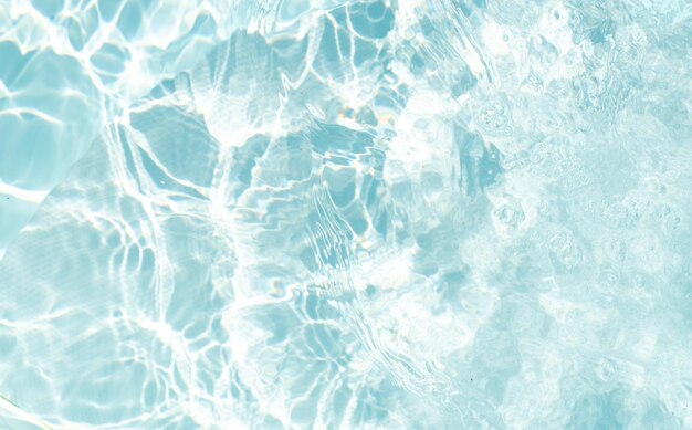 Blurred transparent blue colored clear calm water surface texture with splashes and bubbles Trendy abstract nature background Water waves in sunlight water background