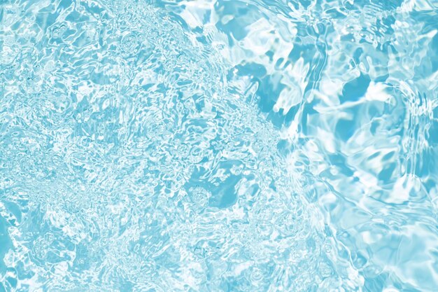 Blurred transparent blue colored clear calm water surface texture with splashes and bubbles Trendy abstract nature background Water waves in sunlight water background