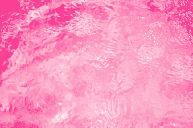 Blurred transparent pink colored clear calm water surface texture with splashes and bubbles Trendy abstract nature background Water waves in sunlight water background