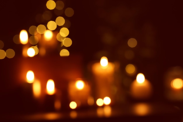 Photo blurred view of beautiful burning candles in darkness
