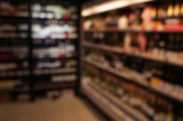 Blurred view of different kinds of wine on shelves in shop